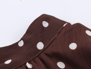 Dettaglio ravvicinato di tessuto chiffon marrone a pois bianchi e cuciture di qualità