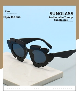Macro shot of black flower-shaped sunglasses with polarized lenses on a marble stand