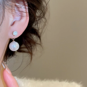 Close-up of vintage zircon and pearl drop earrings on a model for elegant styling
