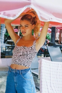 Buitenopname van een vrouw in een zwart-witte crop-top met dierenprint en blauwe denim shorts