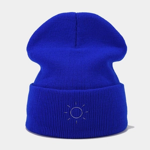 Detail of royal blue ribbed knit beanie featuring white sun embroidery on the folded cuff