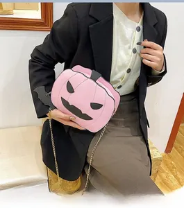 Detailed close-up of pink pumpkin shaped crossbody bag with black bat charm and gold chain