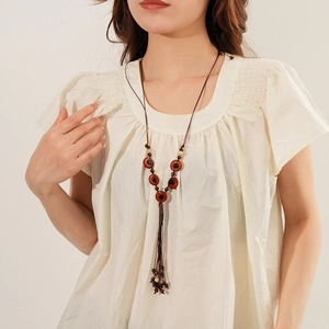 Detail of bohemian necklace with red-brown resin ring and dark brown braided rope texture