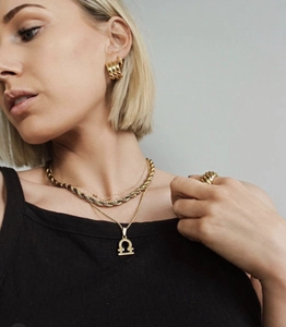 Close-up of gold layered Libra pendant necklace and matching jewelry worn by model