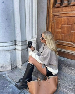 Detail of grey knitted shawl styled with cream sweater and tall black leather boots