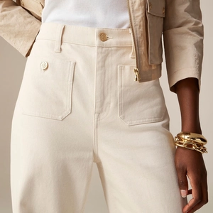 Close-up of high-waist beige twill trousers with cargo pockets and gold embossed metal buttons
