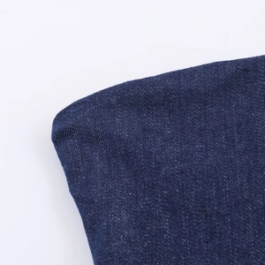 Gros plan sur la texture du denim bleu foncé et les coutures de la robe asymétrique