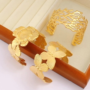 Detailed view of three 18K gold-plated titanium steel bangles with floral and butterfly patterns
