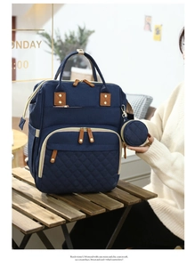 Detail of navy diaper bag with quilted texture and portable crib function on wood table