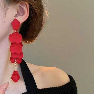 Close-up of elegant red rose petal tassel earrings worn by a model in a side profile
