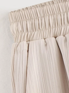 Vue détaillée du tissu plissé beige mettant en valeur la taille élastique extensible