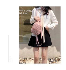 Outdoor street style shot of a mini pink patterned backpack with silver zipper details