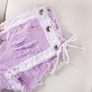 Detalle de shorts vaqueros lila claro con rotos y cordones laterales con ojales