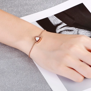 Détail du bracelet géométrique en or rose avec triangle en cristal sur le poignet