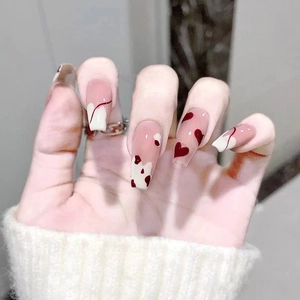 Detailed view of long coffin press-on nails with red hearts and creamy swirl art patterns