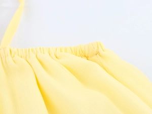 Détail d'une robe en mousseline jaune montrant les bretelles et les plis du décolleté