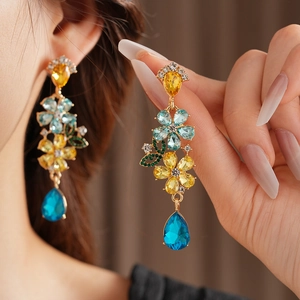 Close-up of vintage gold floral earrings with blue crystals and leaf motifs on a dark background