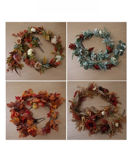 Detail of four fall garlands featuring maple leaves pumpkins and berries on wood surface