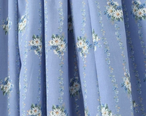 Dettaglio del tessuto blu con motivi di margherite e morbida trama in chiffon