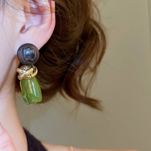 Détail de boucles d'oreilles vintage en résine avec perle brune et pendentif cylindre vert