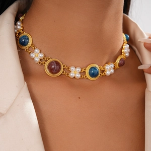 Detail of vintage gold necklace with pearls and colorful resin gems worn on model