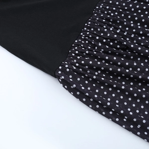 Detail view showing black solid fabric stitched with white polka dot mesh on dress