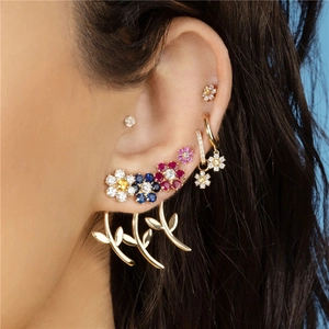 Detailed view of colorful zircon flower earrings and curved leaf pendants on model