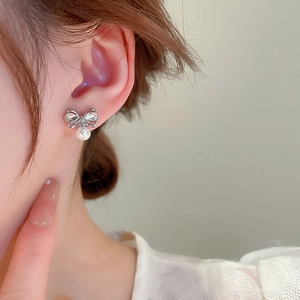 Elegant bow stud earring with diamonds and pearl shown on a model's ear profile