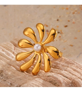 Detail of 18K gold-plated flower ring with white pearl inlay on natural warm background