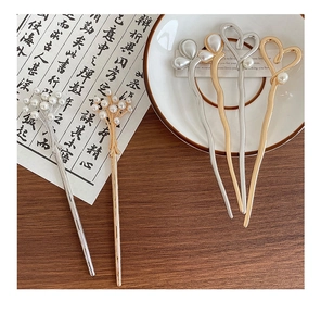 Detailed display of assorted gold and silver pearl hair sticks on a vintage tabletop