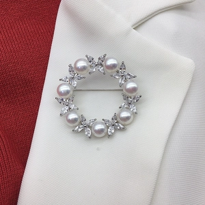 Close-up of a silver floral brooch with natural freshwater pearls and CZ stones on a blazer