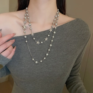 Detail of layered silver beaded necklace featuring star pendants on a female model