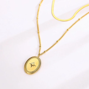 Detail of gold double-layer necklace with snake chain and octagonal star oval pendant
