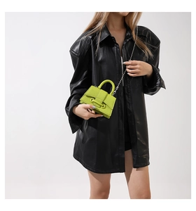Detail of neon green mini beaded chain bag worn with a stylish black leather jacket