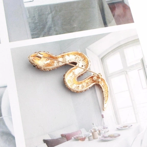 Detailed back view of a golden snake brooch showing the pin clasp and metallic texture