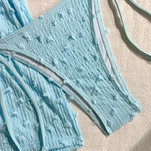 Vista dettagliata del tessuto bikini azzurro con pois trapuntati e finitura arricciata
