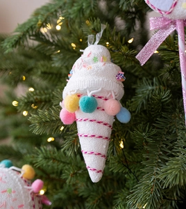 Detail of ice cream cone Christmas ornament with colorful pom-poms on a lit tree
