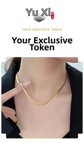Detail view of a sleek gold-plated snake chain necklace on a model for a modern look
