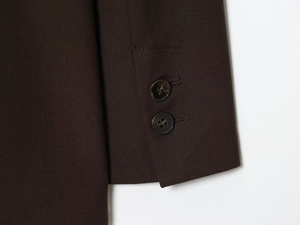 Detail of dark brown blazer cuff with two marble buttons and high density fabric texture