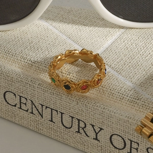 Détail macro d'une bague vintage dorée ornée de pierres colorées sur la tranche d'un livre