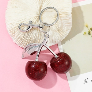 Detail of dark red glitter cherry keychain with silver metal clasp and leaf accents