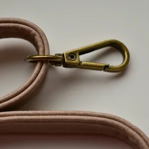 Detail of pink faux suede shoulder strap with vintage bronze swivel lobster clasp