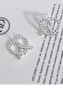 Macro view of silver twisted knot stud earrings on minimalist editorial card