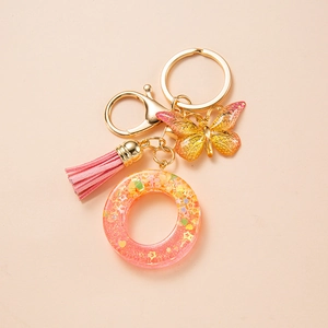 Close-up of pink resin letter O keychain with butterfly charm and soft tassel detail