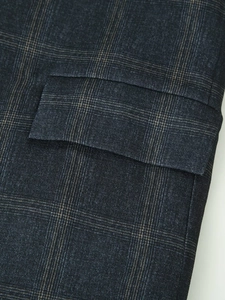 Macro view of navy blue plaid blazer fabric texture with classic pocket flap detail