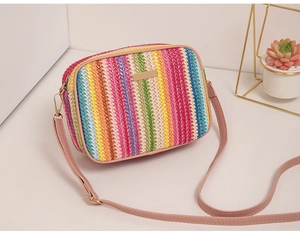 Detail of a vibrant rainbow woven texture crossbody bag with pink faux leather strap