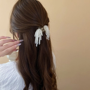 Detailed back view of hair claw clip with faux pearl tassels on wavy brown hair