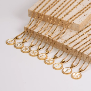 Gold plated stainless steel round shell initial pendant necklaces on travertine stone