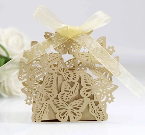 Macro detail of laser-cut butterfly gift box in pearlescent gold with ribbon tie