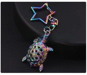 Detailed close-up of a rainbow iridescent metal turtle keychain with a star-shaped ring